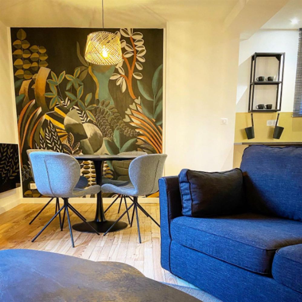Séjour avec fresque végétale et fauteuil bleu